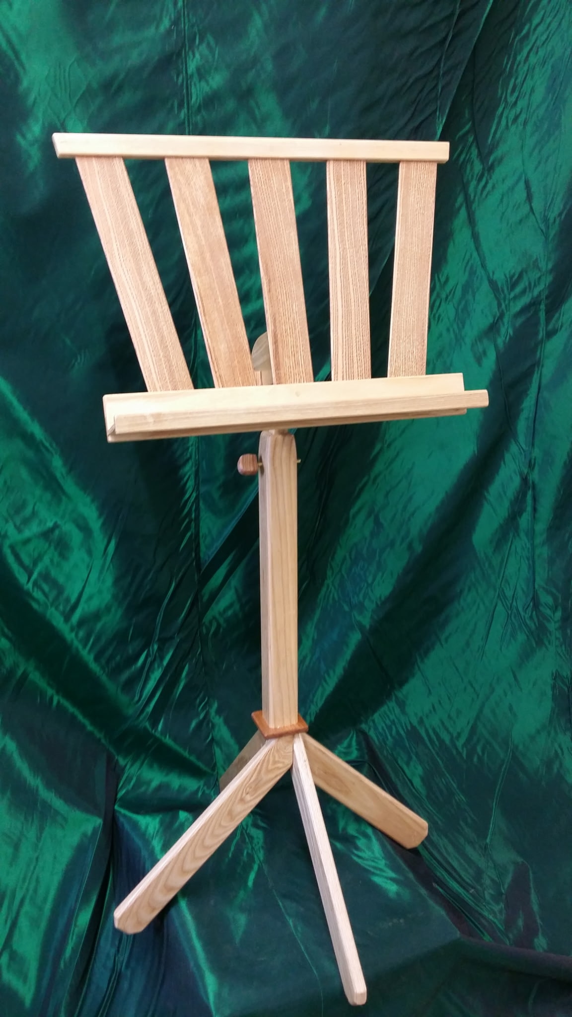 Handcrafted wooden harp music stand against green fabric